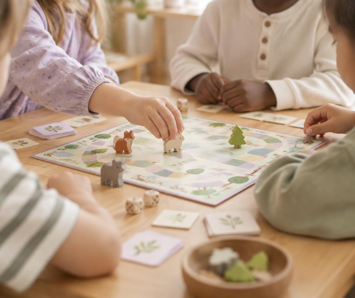 Un petit groupe d'enfants joue ensemble à un jeu de société autour d'une table en bois.